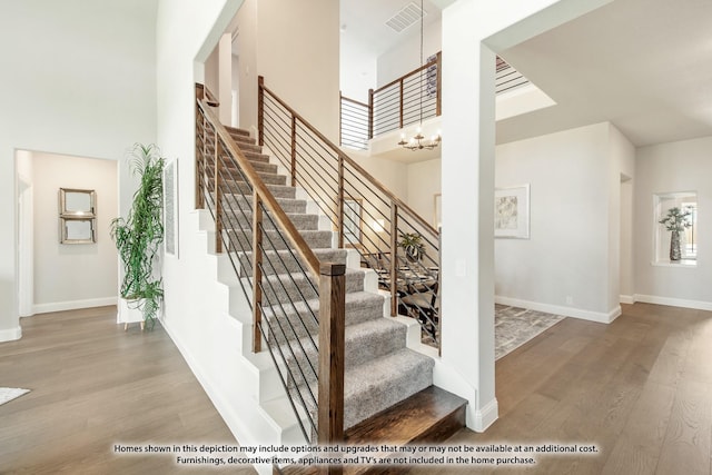 stairway featuring a high ceiling, hardwood / wood-style floors, and a chandelier