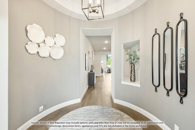 hallway with a chandelier and light wood-type flooring