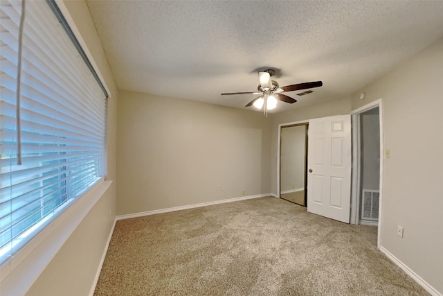 unfurnished bedroom featuring light carpet, a textured ceiling, and ceiling fan