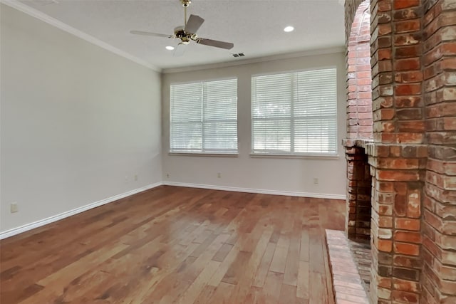 unfurnished living room featuring ceiling fan, ornamental molding, a fireplace, and wood-type flooring