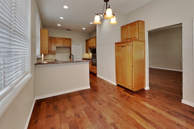 kitchen featuring hanging light fixtures, dark hardwood / wood-style floors, kitchen peninsula, oven, and a chandelier