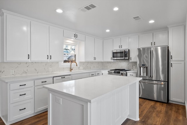 kitchen with sink, white cabinetry, high end appliances, a kitchen island, and dark hardwood / wood-style flooring