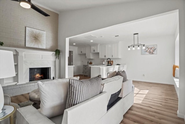 living room featuring a high end fireplace, vaulted ceiling, light hardwood / wood-style flooring, and ceiling fan