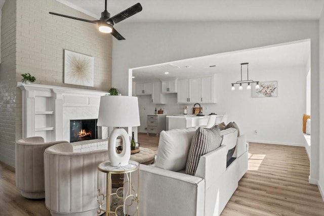 living room featuring light hardwood / wood-style floors, vaulted ceiling, and ceiling fan