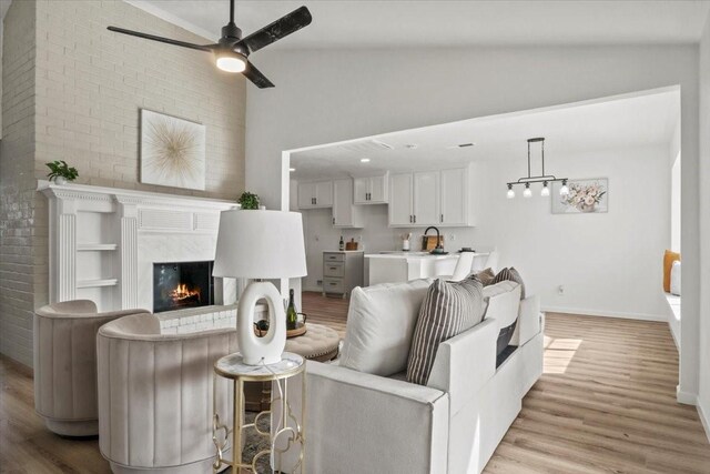 living room with ceiling fan, lofted ceiling, and light wood-type flooring