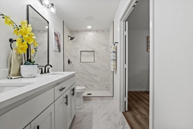 bathroom featuring vanity, toilet, and a tile shower