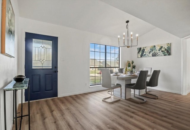 dining area featuring hardwood / wood-style floors, a notable chandelier, and lofted ceiling