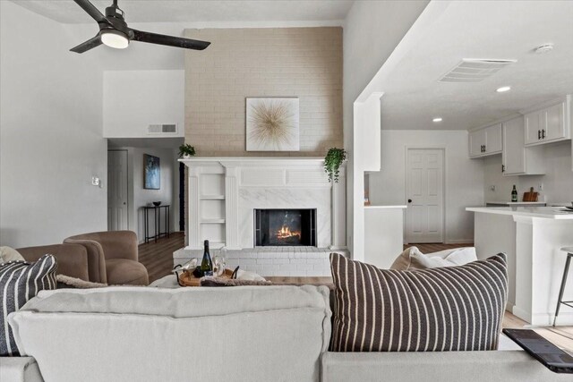 living room featuring ceiling fan, light hardwood / wood-style floors, and a high end fireplace