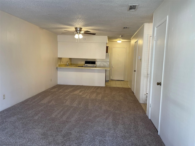 kitchen featuring light carpet, stainless steel refrigerator, kitchen peninsula, ceiling fan, and white cabinets