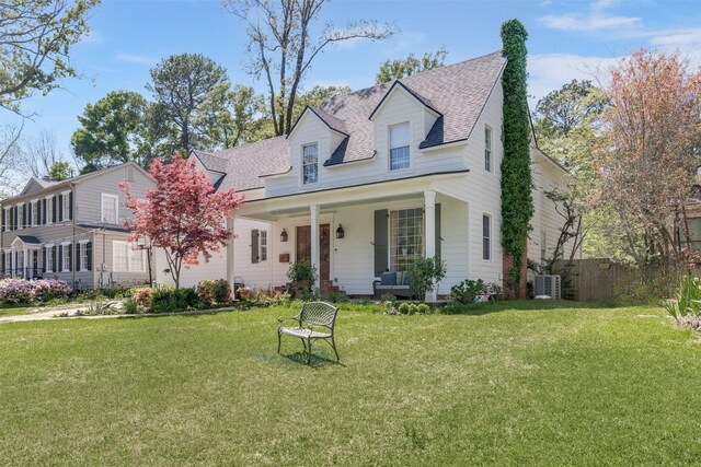 new england style home featuring covered porch, central air condition unit, and a front yard