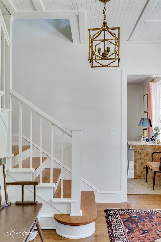 stairway featuring wood-type flooring and a notable chandelier