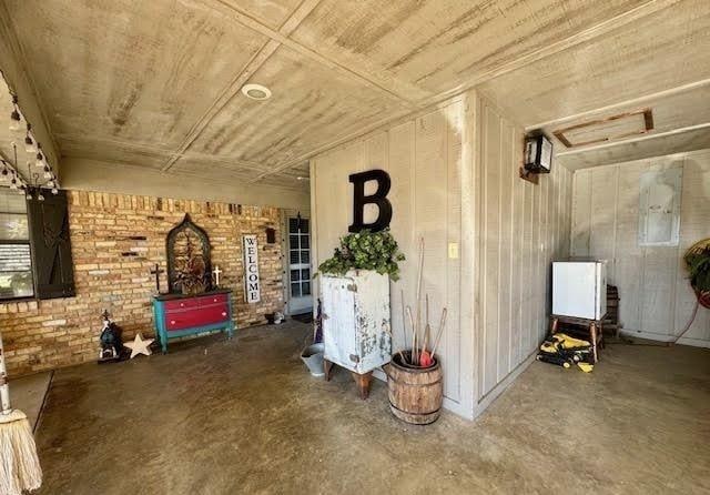 interior space featuring electric panel, concrete flooring, and brick wall