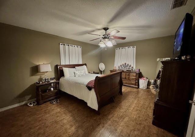 bedroom featuring ceiling fan, dark hardwood / wood-style flooring, and a textured ceiling