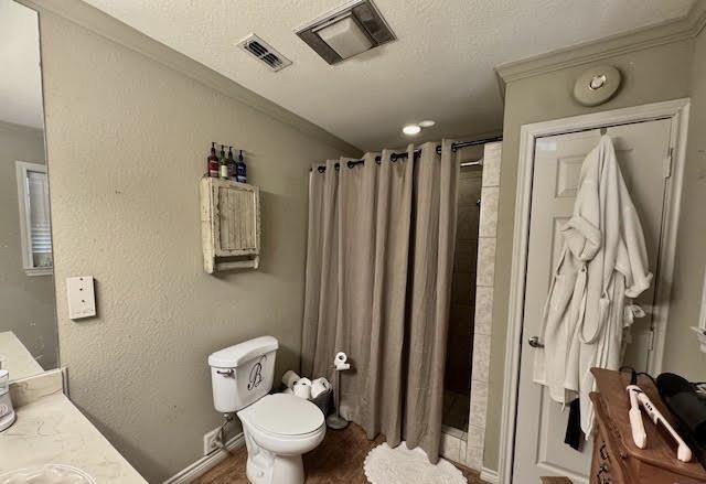 bathroom featuring curtained shower, vanity, toilet, crown molding, and a textured ceiling