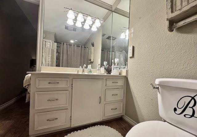 bathroom with walk in shower, vanity, wood-type flooring, toilet, and lofted ceiling