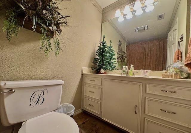 bathroom with crown molding, vanity, and toilet