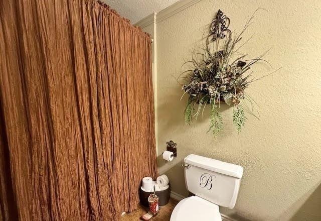 bathroom with ornamental molding and toilet