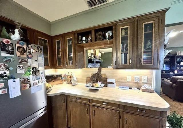 kitchen with dark brown cabinets, butcher block counters, and stainless steel refrigerator