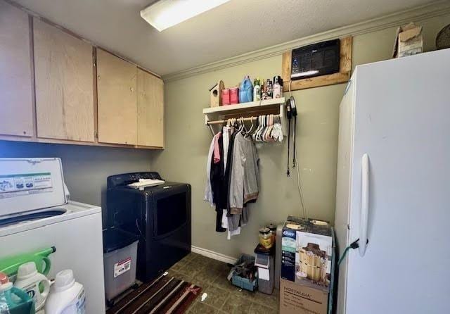 clothes washing area featuring cabinets and washer and clothes dryer