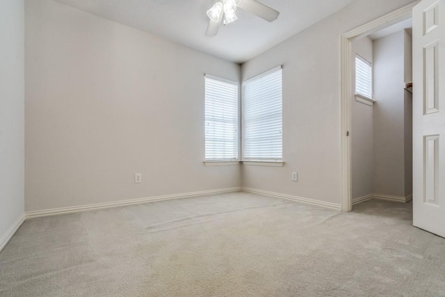 spare room with light colored carpet, a wealth of natural light, and ceiling fan