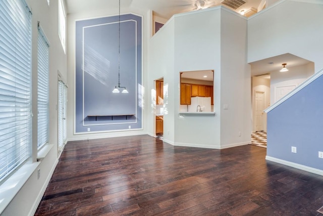 unfurnished living room featuring plenty of natural light, dark hardwood / wood-style floors, and a high ceiling