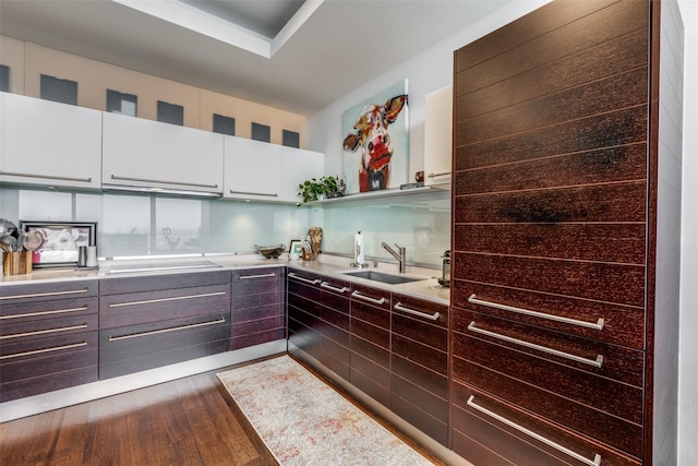 kitchen with white cabinetry, sink, dark wood-type flooring, cooktop, and dark brown cabinets