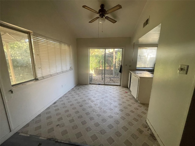 kitchen with lofted ceiling, white cabinetry, and ceiling fan