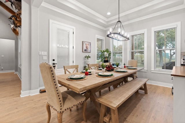 dining room with a raised ceiling, light hardwood / wood-style flooring, and a notable chandelier