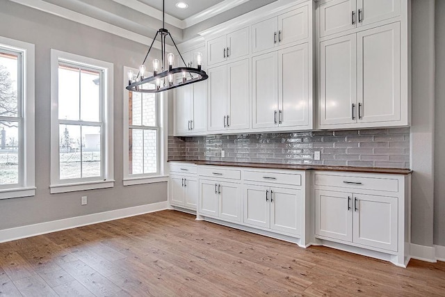 kitchen featuring pendant lighting, wood counters, a healthy amount of sunlight, and light hardwood / wood-style flooring