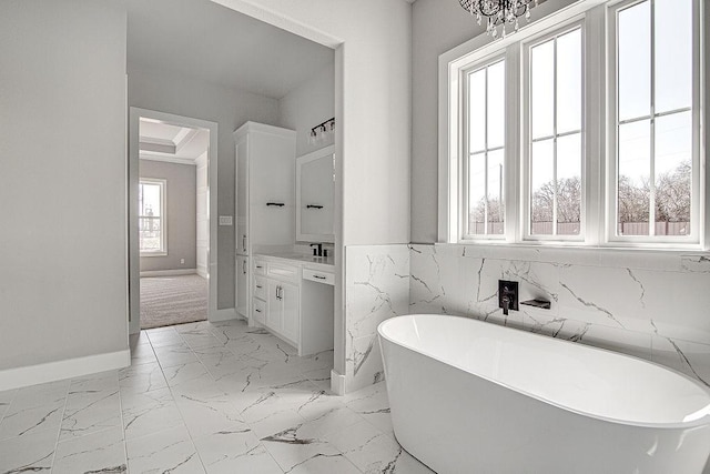 bathroom featuring a chandelier, vanity, tile walls, and a tub