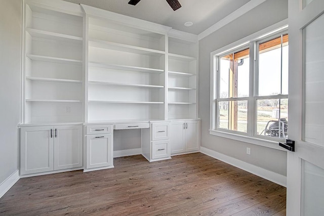 unfurnished office featuring ceiling fan, light wood-type flooring, and built in shelves