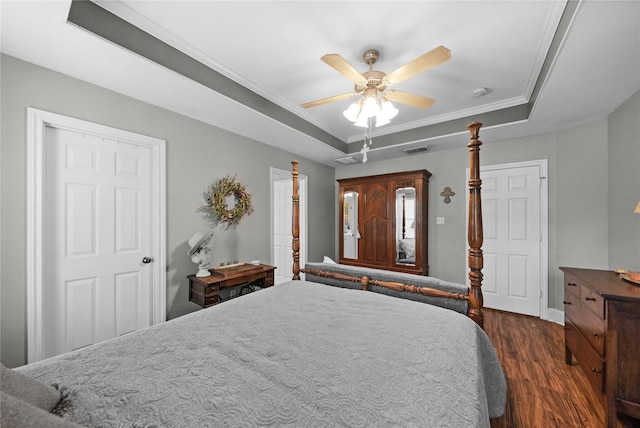 bedroom with a tray ceiling, ceiling fan, dark wood-type flooring, and ornamental molding