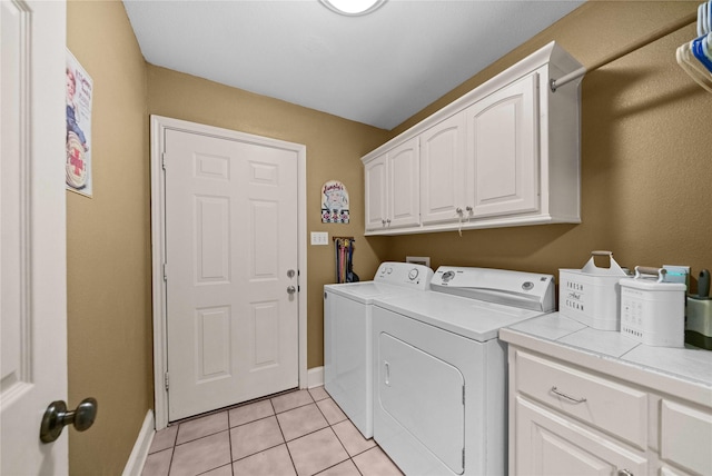 washroom with washing machine and dryer, light tile patterned flooring, and cabinets