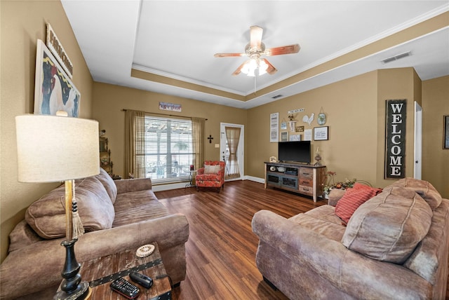 living room featuring a raised ceiling, ceiling fan, dark wood-type flooring, and crown molding