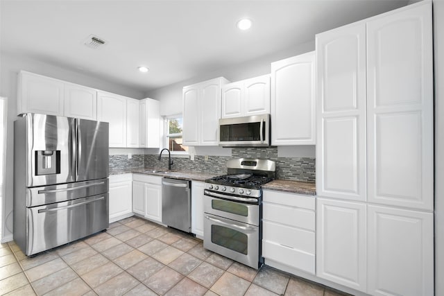 kitchen with sink, dark stone counters, decorative backsplash, white cabinets, and appliances with stainless steel finishes