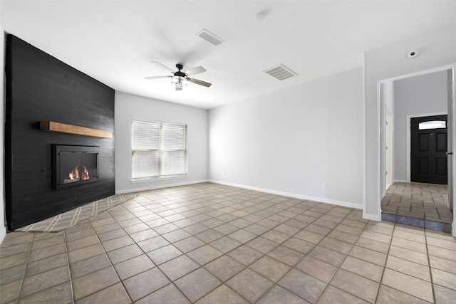 unfurnished living room with ceiling fan, a large fireplace, and light tile patterned floors