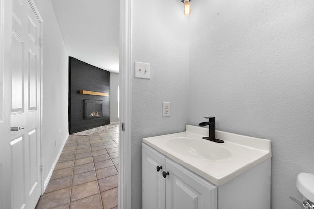 bathroom featuring tile patterned floors, a large fireplace, vanity, and toilet