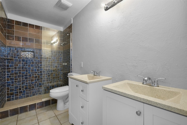 bathroom featuring tile patterned floors, a tile shower, vanity, a textured ceiling, and toilet