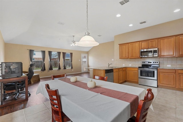 kitchen with stainless steel appliances, ceiling fan, sink, decorative light fixtures, and light hardwood / wood-style flooring