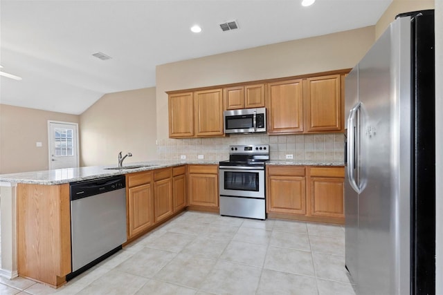 kitchen featuring kitchen peninsula, light stone counters, stainless steel appliances, sink, and lofted ceiling