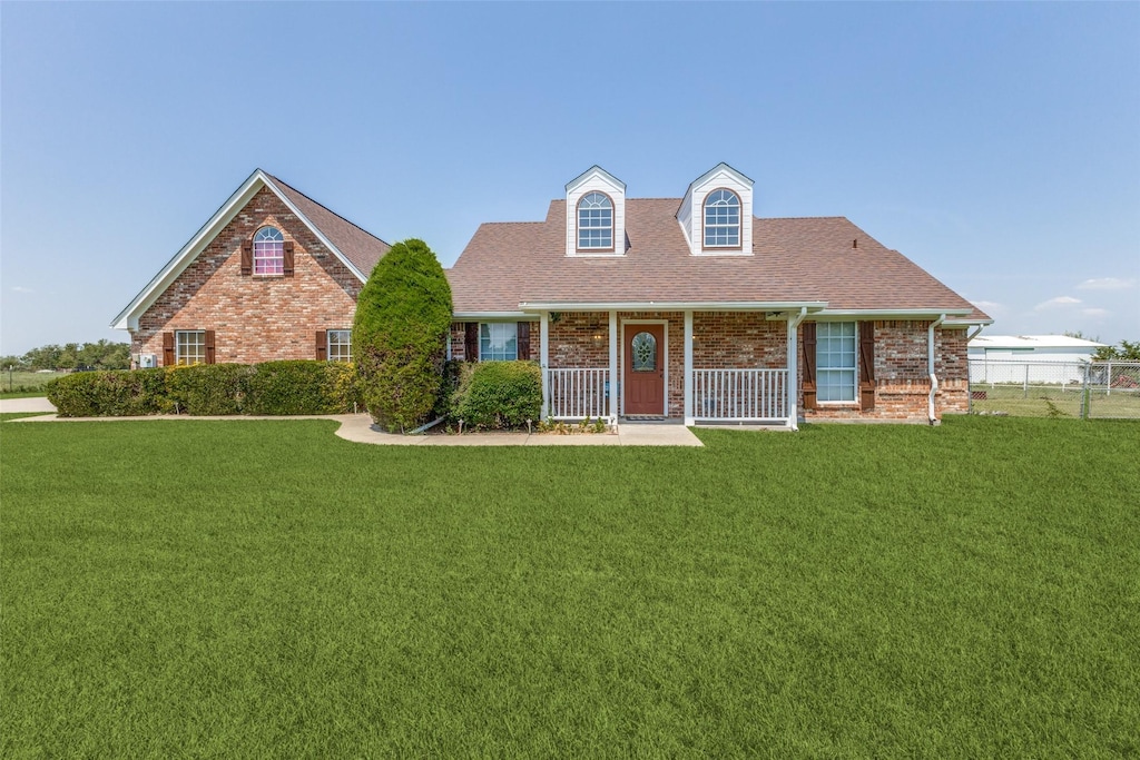 cape cod house featuring a porch and a front lawn