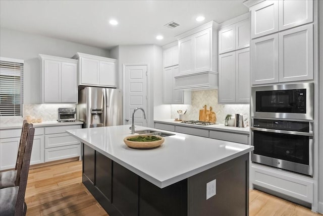 kitchen with white cabinets, sink, light wood-type flooring, and stainless steel appliances