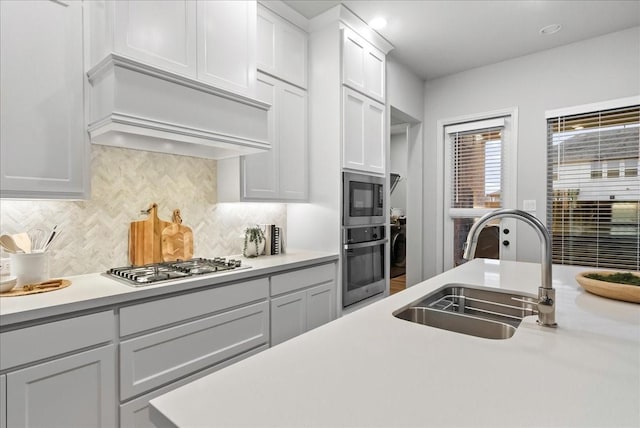 kitchen with custom exhaust hood, sink, decorative backsplash, and stainless steel appliances