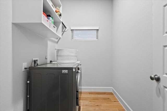 laundry area featuring washing machine and dryer and light hardwood / wood-style flooring