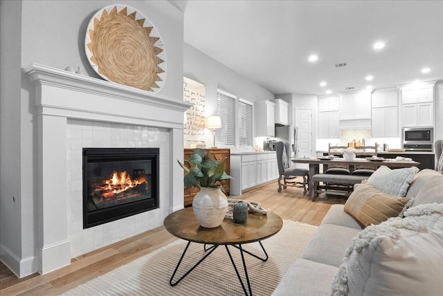 living room featuring a tile fireplace and light hardwood / wood-style flooring