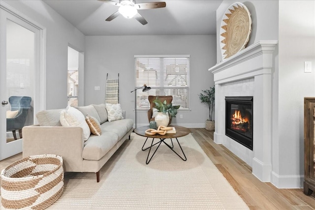 living room with ceiling fan, light wood-type flooring, and a fireplace