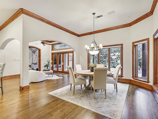 dining room featuring wood-type flooring, a healthy amount of sunlight, a chandelier, and a towering ceiling