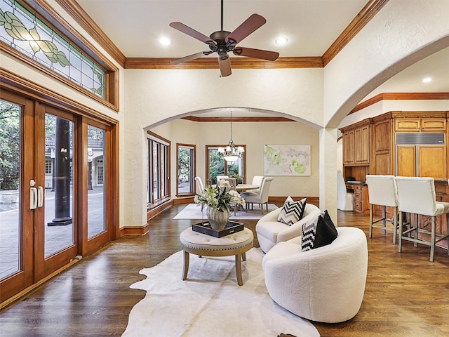 living room featuring ceiling fan with notable chandelier, crown molding, dark wood-type flooring, and french doors