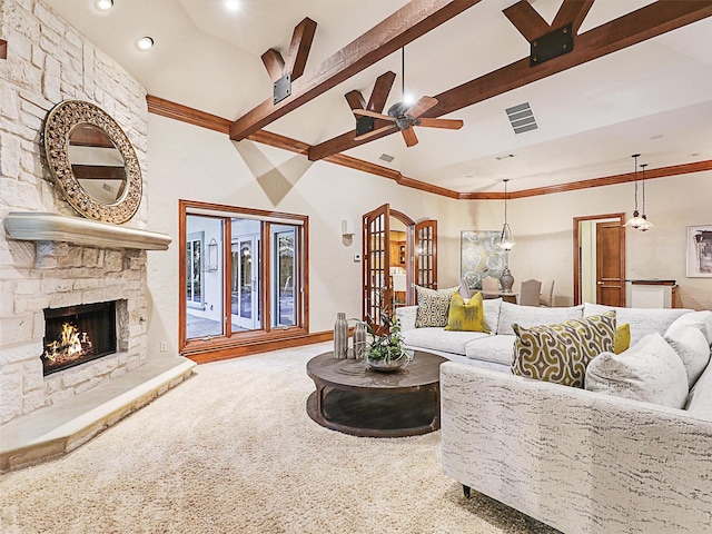 living room featuring ceiling fan, carpet floors, ornamental molding, a stone fireplace, and beamed ceiling