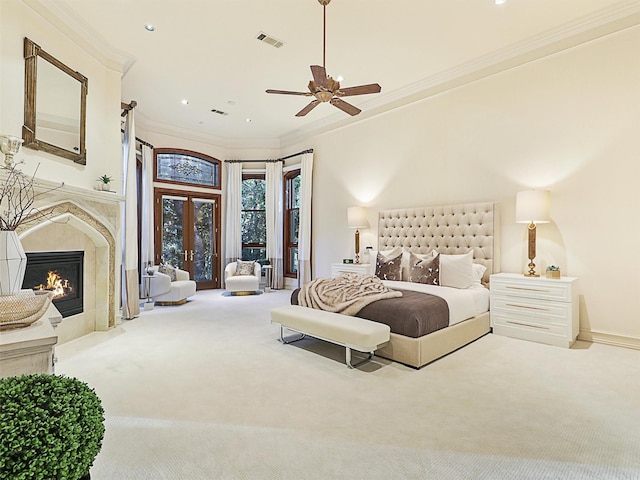 bedroom featuring french doors, crown molding, ceiling fan, light colored carpet, and a premium fireplace